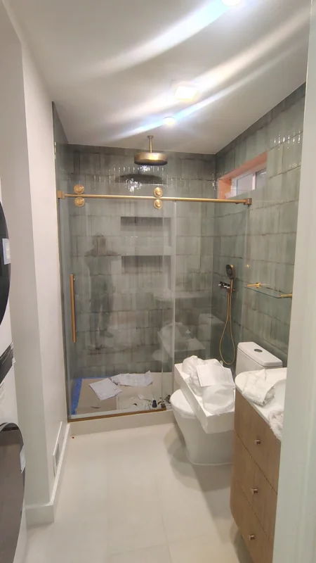 A tiled shower enclosure with glass doors and warm metal accents.
