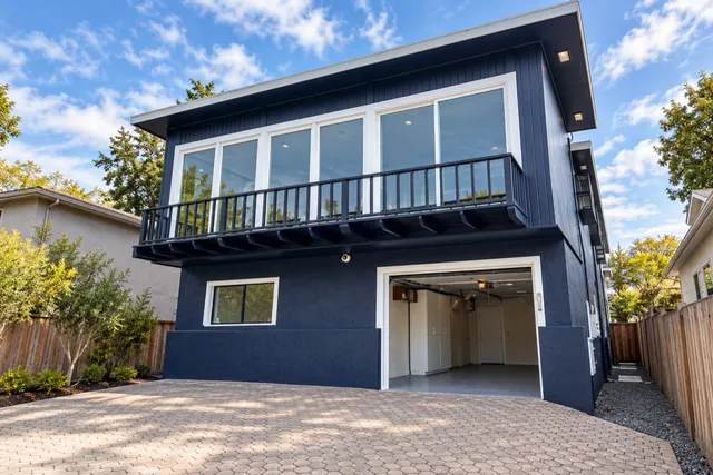 Deep blue siding, white trim, and a coordinated balcony finish.