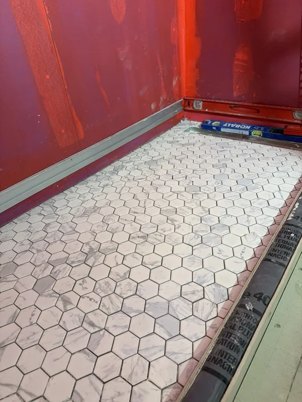A mosaic shower floor and wall preparation during installation.